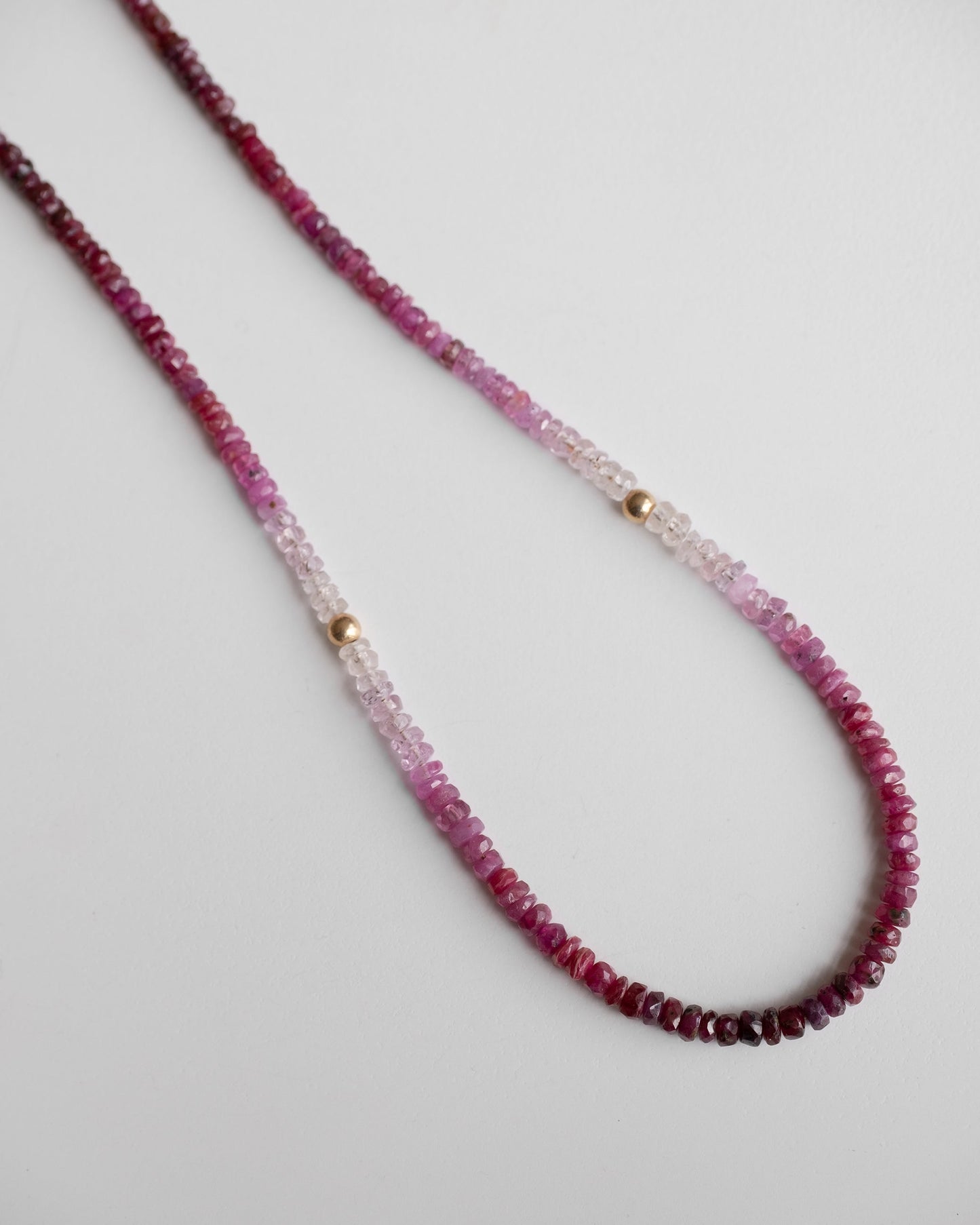 gold beaded necklace with shaded ruby gemstones and two little gold balls