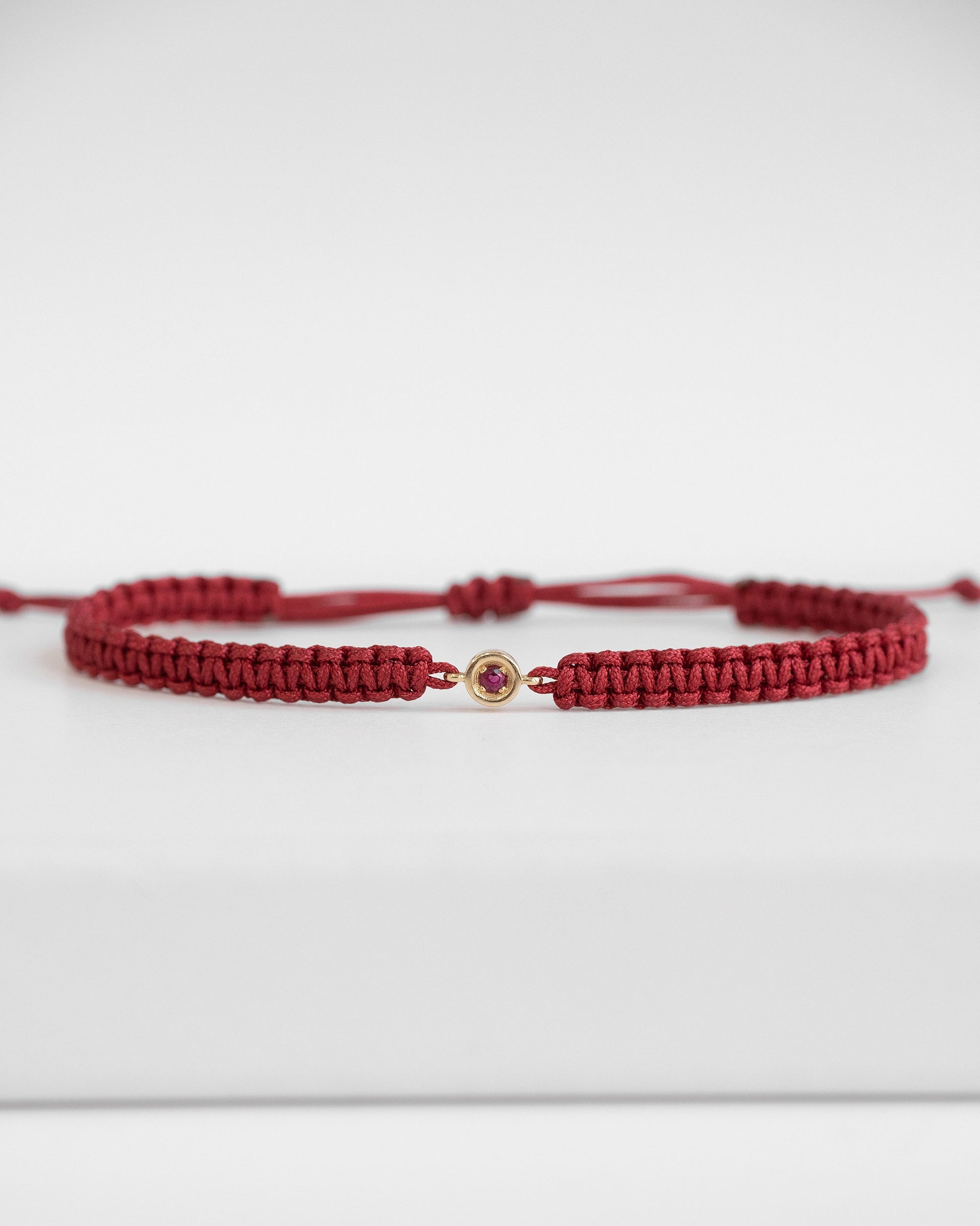red cord bracelet with ruby and gold clasp