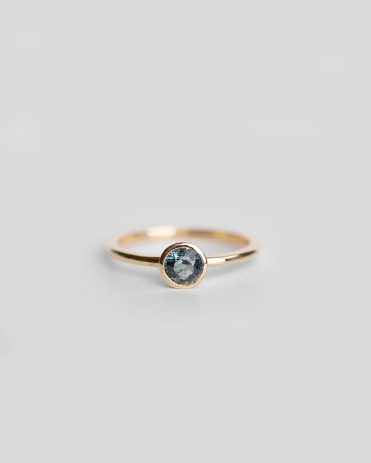 solitaire gold ring with bezel set teal sapphire