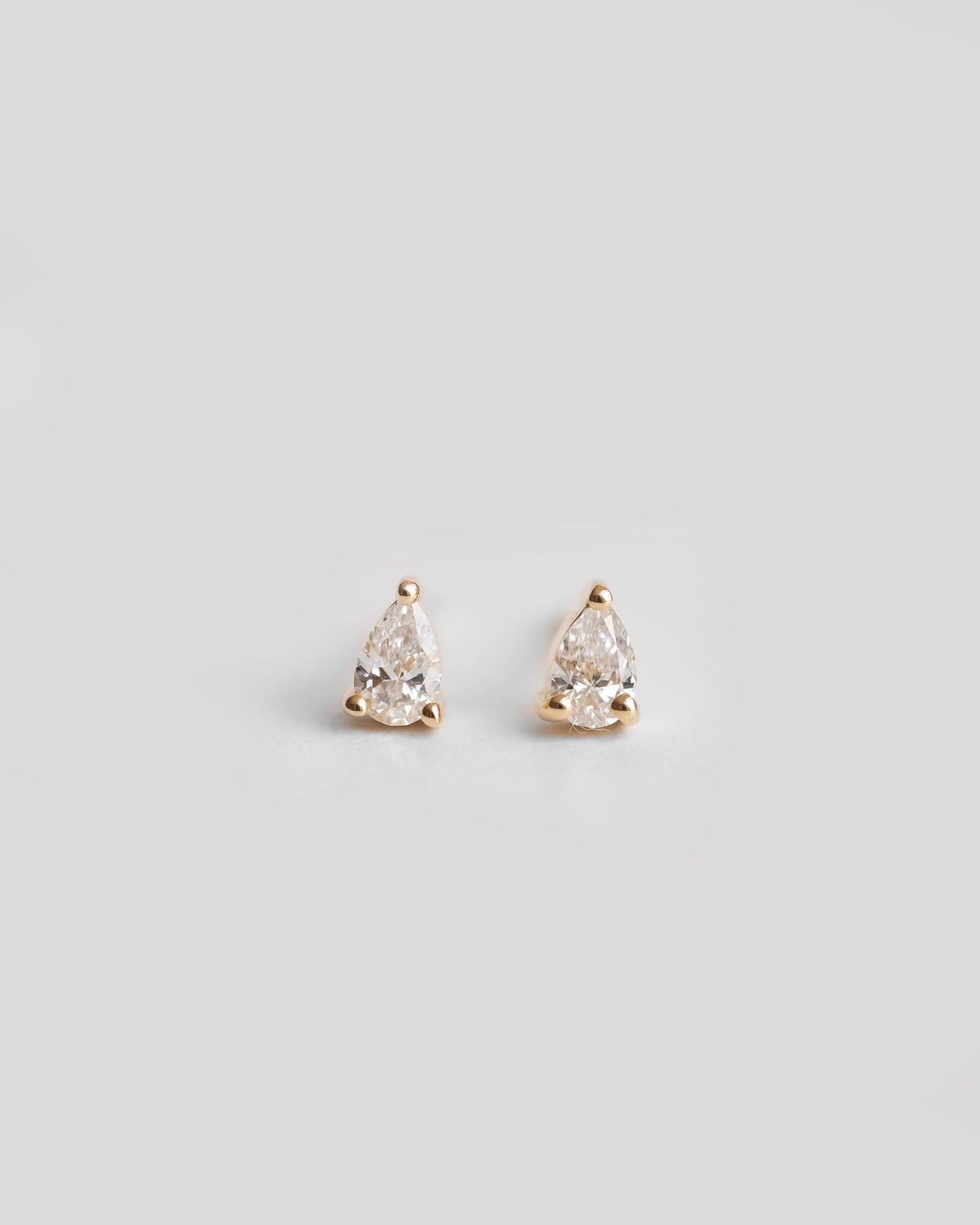 a pair of gold earrings with a single diamond