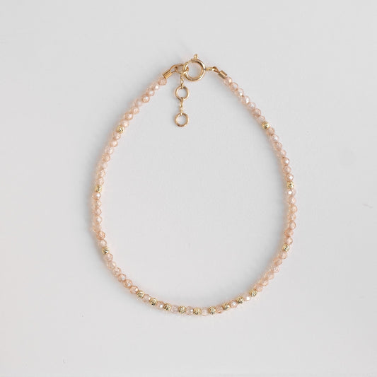 solid gold bracelet with delicate zirconia stones, beige beaded gold bracelet